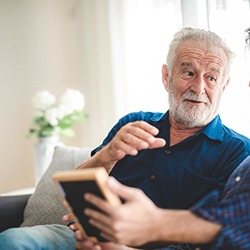 A senior man talking to a younger man