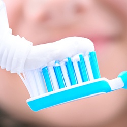 Closeup of white toothpaste squeezed onto blue and white toothbrush