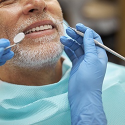 Nose-to-shoulder view of man with white beard undergoing dental exam