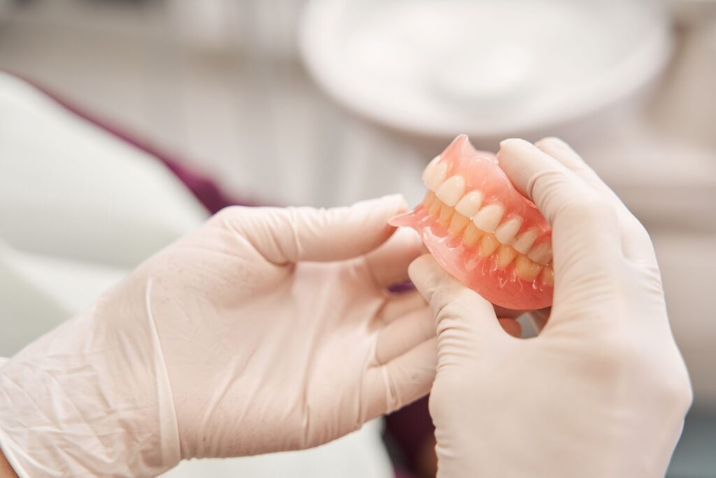 White-gloved hands holding complete set of dentures